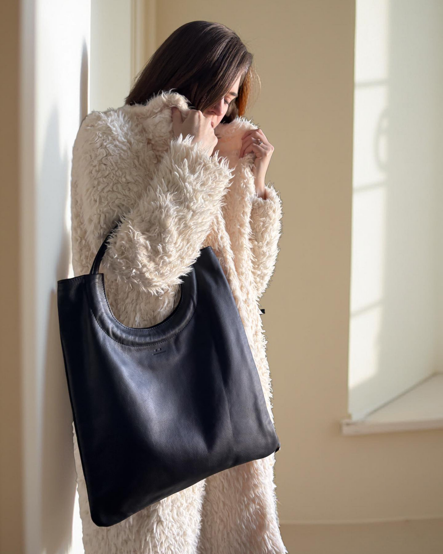 noir black reversible leather and suede tote bag and woman in white coat